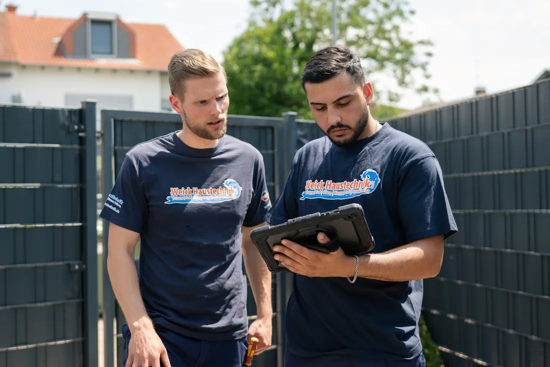 Zwei Mitarbeiter von Weick schauen gemeinsam auf ein Tablet