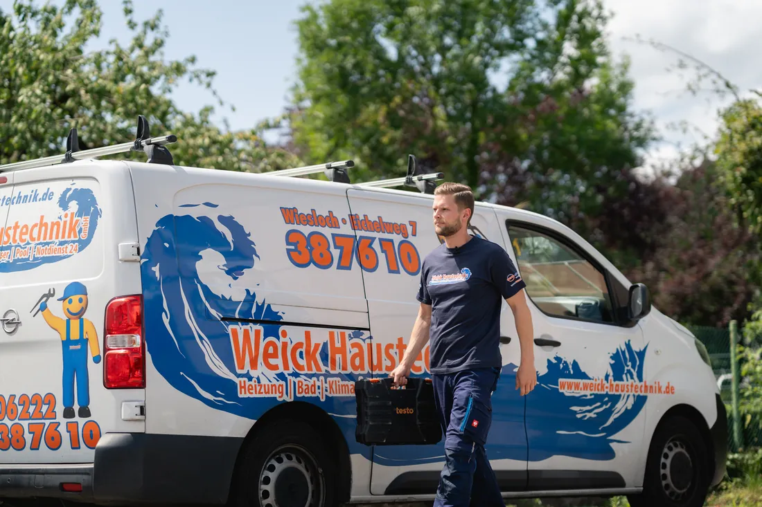 Monteur von Weick mit Werkzeugkoffer am Firmenwagen